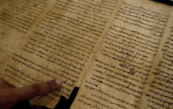 An Israel Museum worker points at the word "Jerusalem" written in a part of the Isaiah Scroll, one of the Dead Sea Scrolls, inside the vault of the Shrine of the Book building at the Israel Museum in Jerusalem on Monday. 